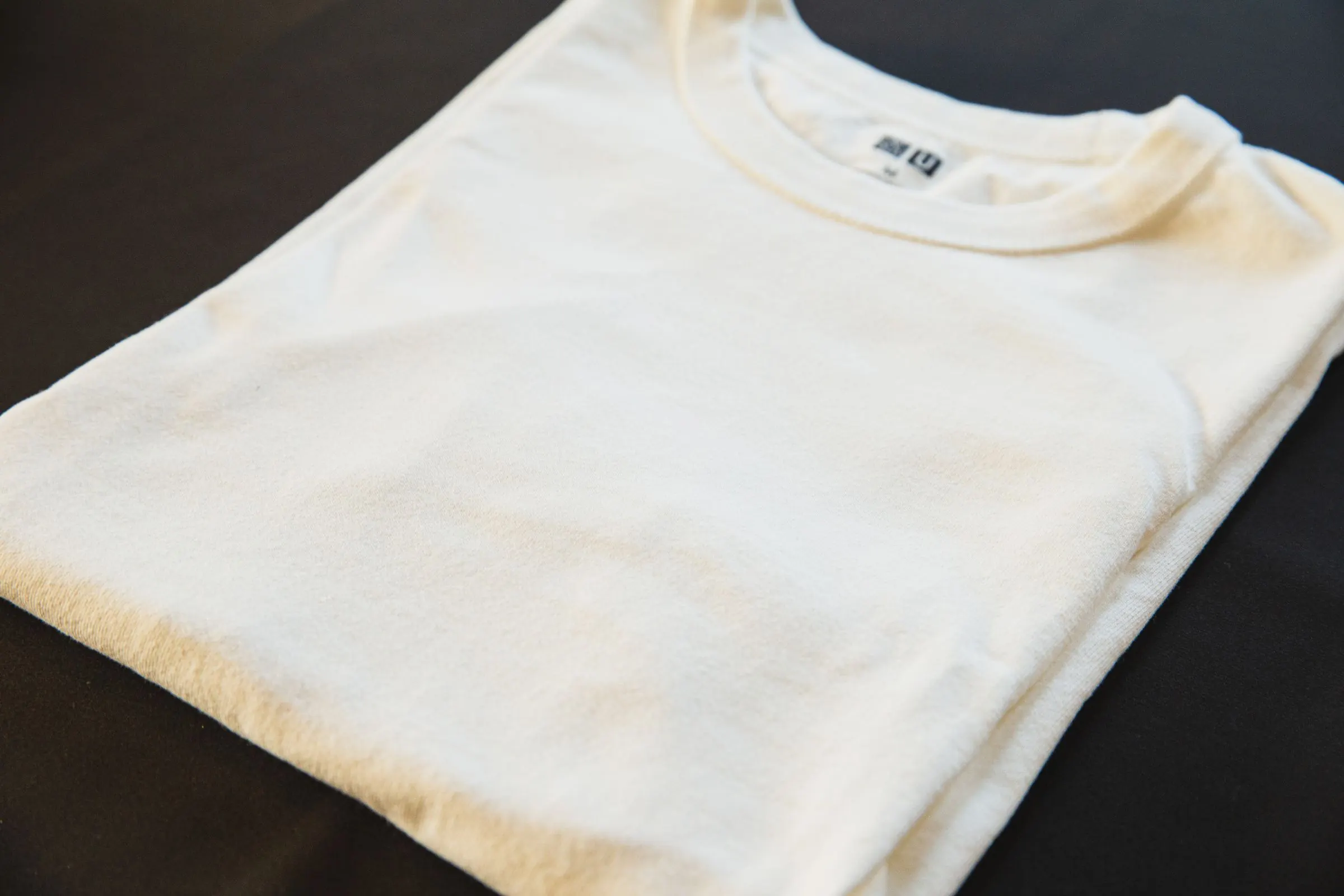 Detalhe de uma camiseta branca dobrada sobre fundo escuro