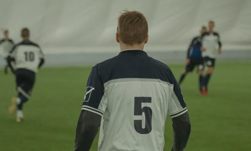 Jogador vestindo camisa e calção de uniforme esportivo em campo